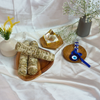 Smudging sage sticks for spiritual cleansing, crystal pyramid, and blue evil eye charm on a wooden plate
